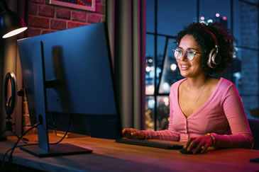 Dedicated Female Student Utilizing a Computer to Prepare for Real Estate Exam Prep with Night City Background while in her home - NightBeforeTheExam.com for Comprehensive Real Estate Study